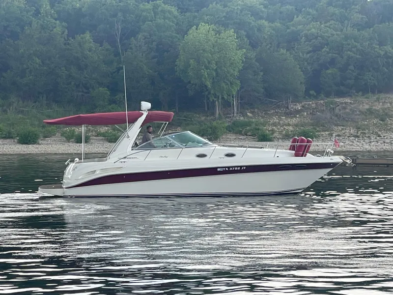The Image of 2001 Sea Ray 340 Sundancer boat on calm water with forested shoreline. - 0