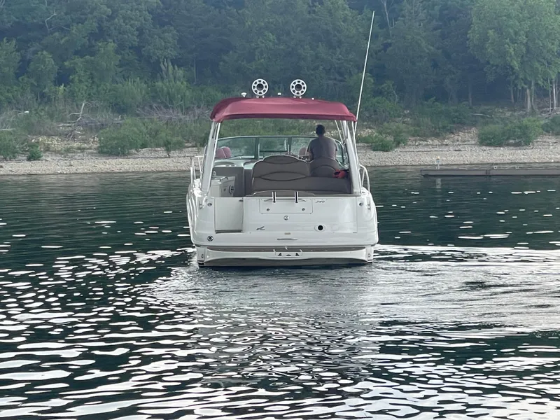 Slide: The Image of 2001 Sea Ray 340 Sundancer boat on calm water with red canopy, near a wooded shoreline. - 3