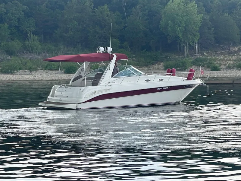 Slide: The Image of 2001 Sea Ray 340 Sundancer boat cruising on a calm lake with forested shoreline. - 4