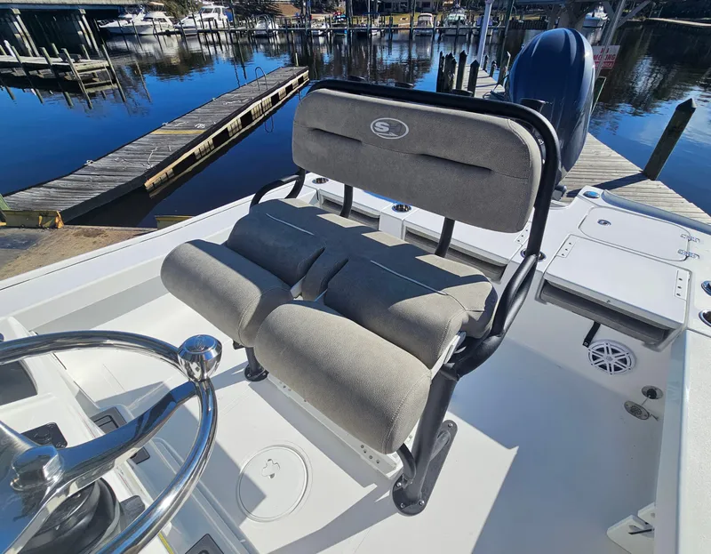 Slide: The Image of 2026 Sea Hunt BX 22 BR boat interior with cushioned seating and steering wheel, dockside view. - 13