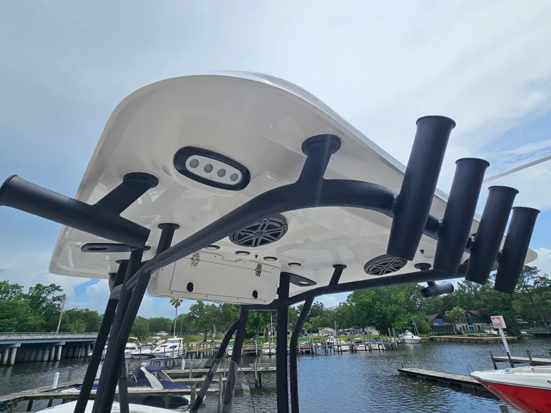 Slide: The Image of 2025 Sea Hunt Ultra 219 boat with rod holders and speakers, docked by a scenic waterfront. - 24