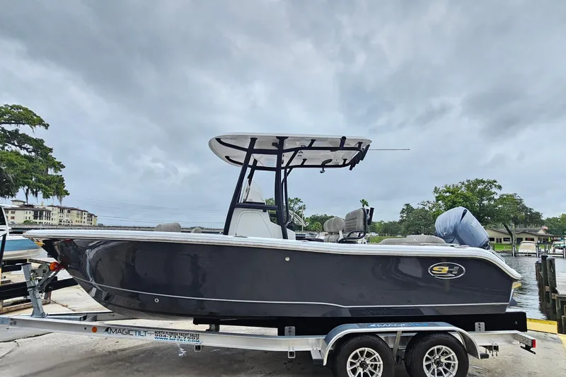 Slide: The Image of 2026 Sea Hunt Ultra 219 boat on trailer, dockside, under cloudy sky. - 3