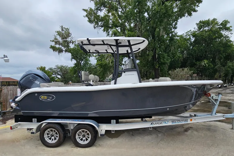 Slide: The Image of 2026 Sea Hunt Ultra 219 boat on trailer, parked outdoors with trees in background. - 4