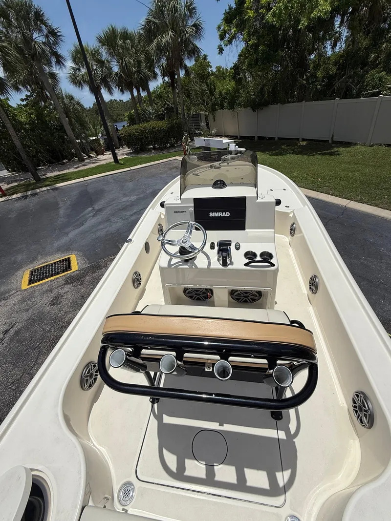 Slide: The Image of 2017 Yellowfin 24 Bay CE boat interior with steering console, rod holders, and palm trees in the background. - 5