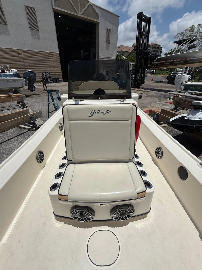 Slide: The Image of 2017 Yellowfin 24 Bay CE boat with cushioned seating and cup holders, docked outdoors. - 7