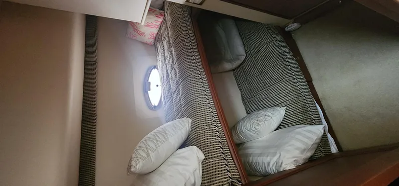 Slide: The Image of 2004 Silverton 48 Convertible yacht cabin with twin beds and porthole window. - 28
