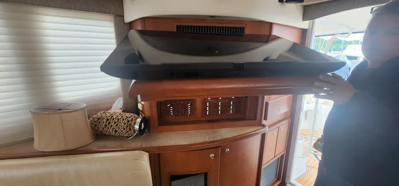 Slide: The Image of 2004 Silverton 48 Convertible yacht interior with TV, wooden cabinetry, and lamp. - 36