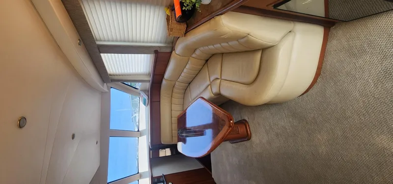 Slide: The Image of Interior of 2004 Silverton 48 Convertible yacht with beige leather seating and wooden table. - 5