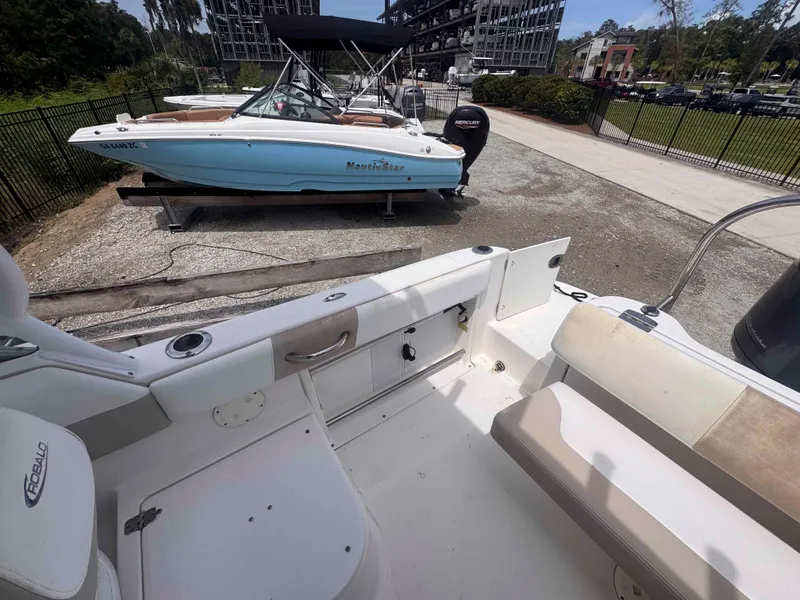 Slide: The Image of 2019 Robalo R227 Dual Console boat interior with seating and storage, parked outdoors. - 10