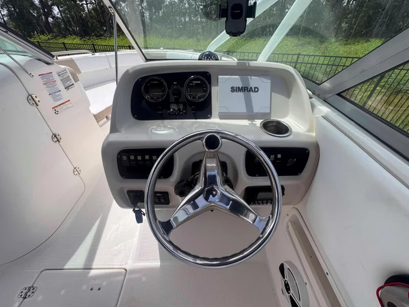 Slide: The Image of 2019 Robalo R227 Dual Console boat dashboard with steering wheel and Simrad display. - 13