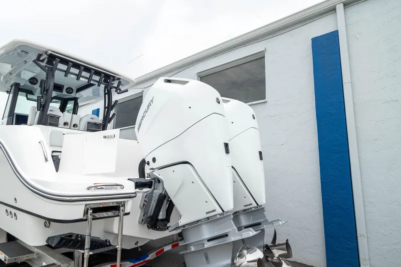 Slide: The Image of 2026 Crevalle 33 CSF boat with dual outboard engines, parked near a building. - 10