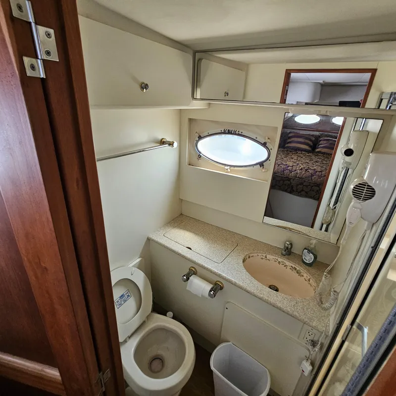 Slide: The Image of Bathroom interior of 2000 Silverton 392 Motor Yacht with sink, toilet, and porthole window. - 34