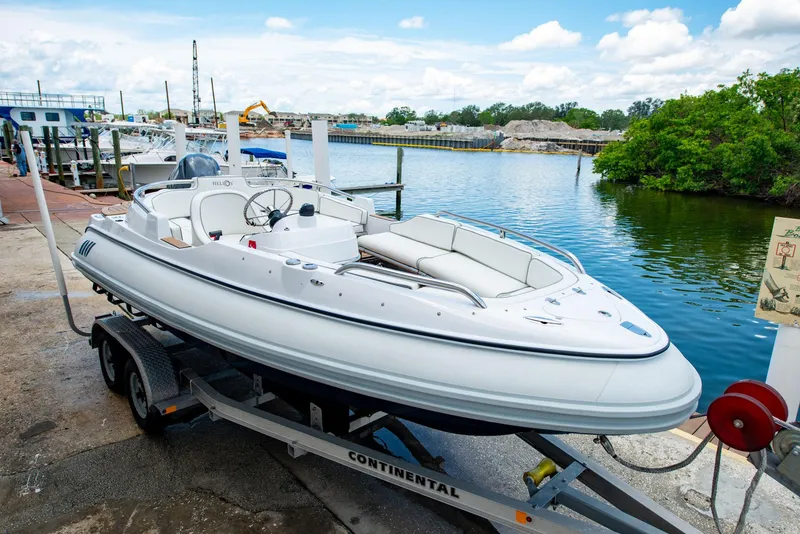Slide: The Image of 2006 Novurania RHIB boat on trailer by waterfront, under clear blue sky. - 10