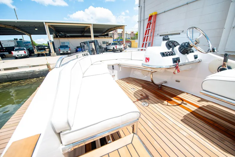 Slide: The Image of 2006 Novurania RHIB with white seating and wooden deck, docked near a marina. - 12