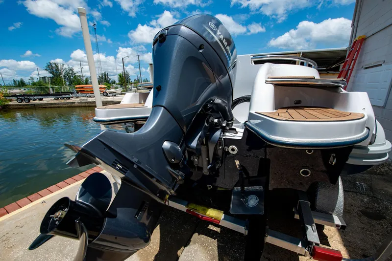 Slide: The Image of 2006 Novurania RHIB with outboard motor, docked by a serene waterfront under a blue sky. - 17