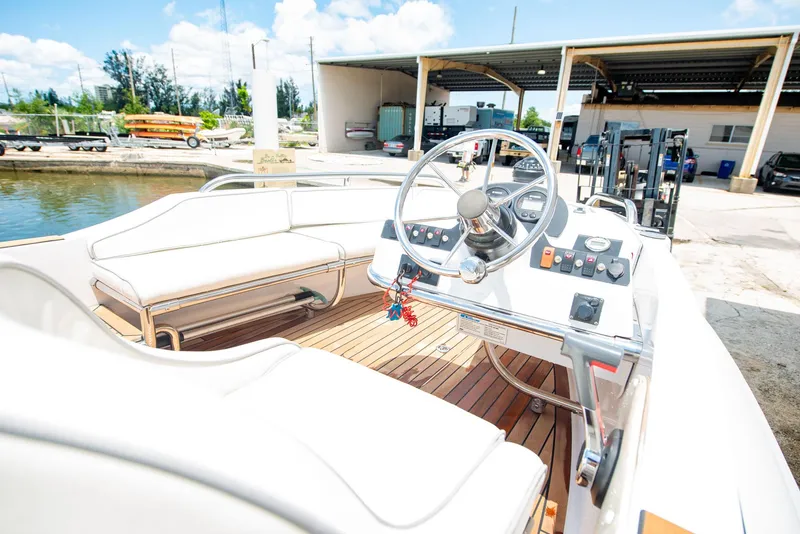 Slide: The Image of 2006 Novurania RHIB boat with white seating and steering wheel, docked near a marina. - 8