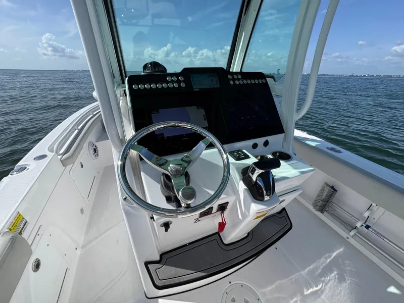 Slide: The Image of 2022 Everglades 235 Center Console boat dashboard with steering wheel, controls, and ocean view. - 18
