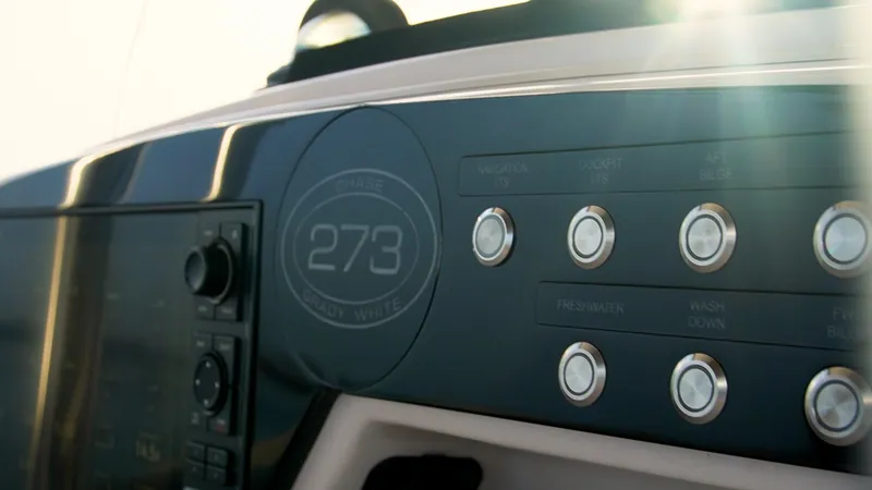 Slide: The Image of Grady-White 273 Chase CC 2025 boat dashboard with control buttons and sunlight. - 20