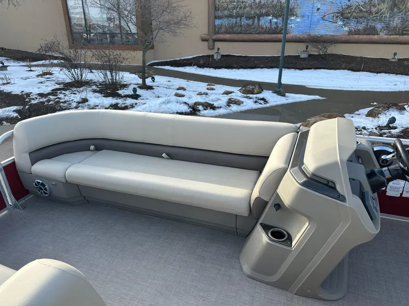 Slide: The Image of 2025 Sun Tracker Party Barge 18 DLX interior with beige seating and helm, snowy background. - 4