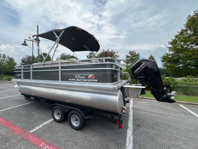 Slide: The Image of 2025 Sun Tracker Fishin' Barge 20 DLX pontoon boat on trailer in parking lot. - 8