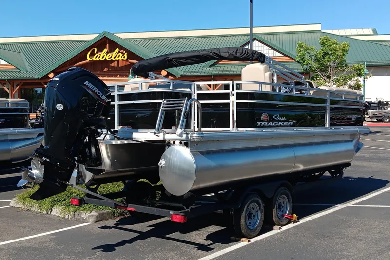 Slide: The Image of 2025 Sun Tracker SportFish 20 DLX pontoon boat parked at Cabela's. - 2
