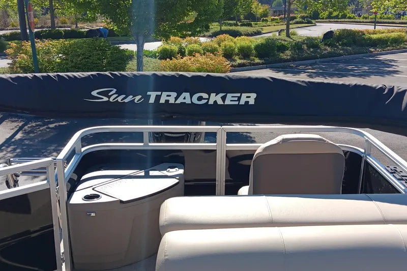 Slide: The Image of 2025 Sun Tracker SportFish 20 DLX boat interior with seating and cover in a sunny setting. - 5