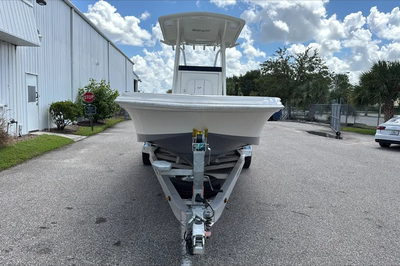 Slide: The Image of 2025 Ranger 2360 Bay boat on trailer, parked outdoors under a cloudy sky. - 2