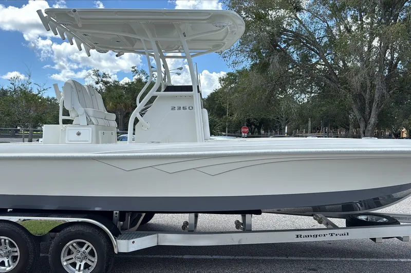 Slide: The Image of 2025 Ranger 2360 Bay boat on trailer, parked outdoors under a clear sky. - 1