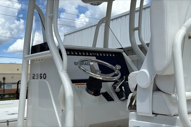 Slide: The Image of 2025 Ranger 2360 Bay boat console with steering wheel and controls, under a cloudy sky. - 4