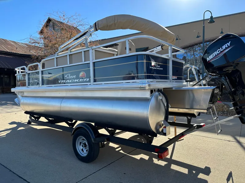 Slide: The Image of 2025 Sun Tracker Bass Buggy 18 DLX pontoon boat on trailer, featuring Mercury outboard motor. - 2