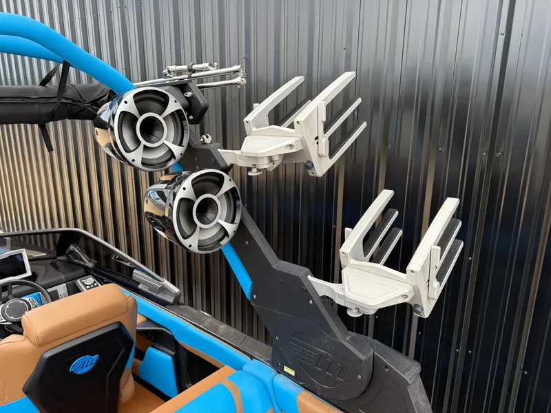 Slide: The Image of 2021 Malibu M240 boat with wakeboard racks and speakers, featuring blue and brown interior. - 11