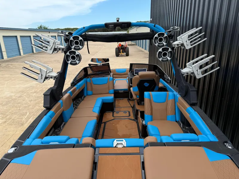 Slide: The Image of 2021 Malibu M240 boat with blue and brown interior, featuring multiple speakers and wakeboard racks. - 13