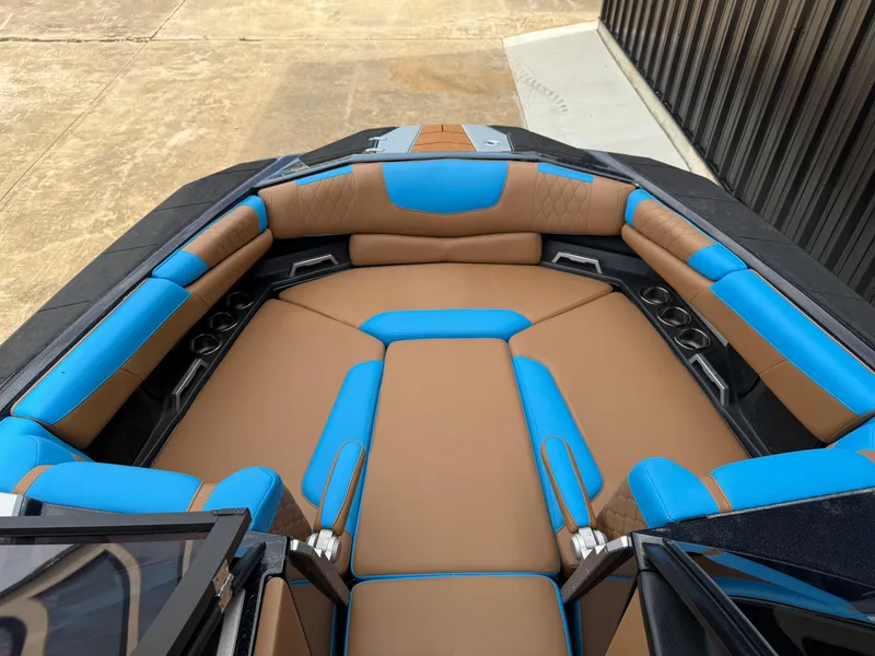 Slide: The Image of 2021 Malibu M240 boat interior with blue and brown seating, cup holders, and sleek design. - 4