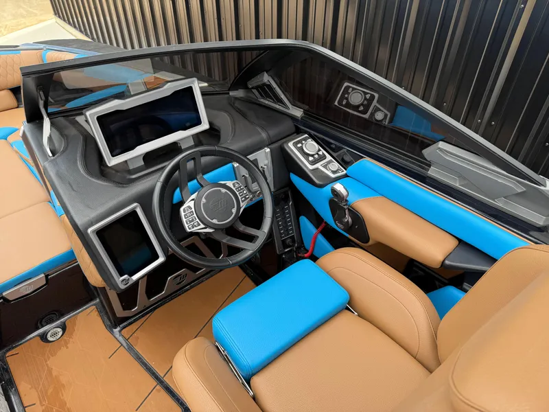 Slide: The Image of 2021 Malibu M240 boat interior with modern dashboard, steering wheel, and blue-brown seating. - 6
