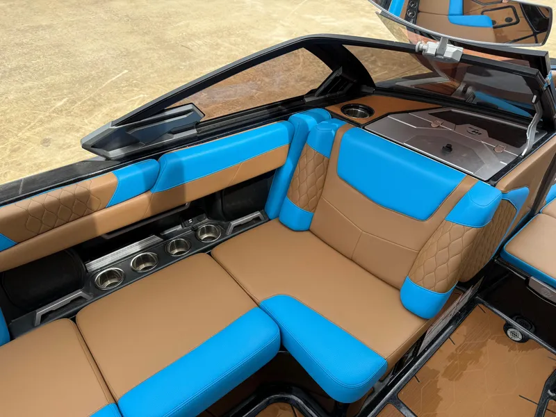 Slide: The Image of 2021 Malibu M240 boat interior with blue and brown seating, cup holders, and sleek design. - 8