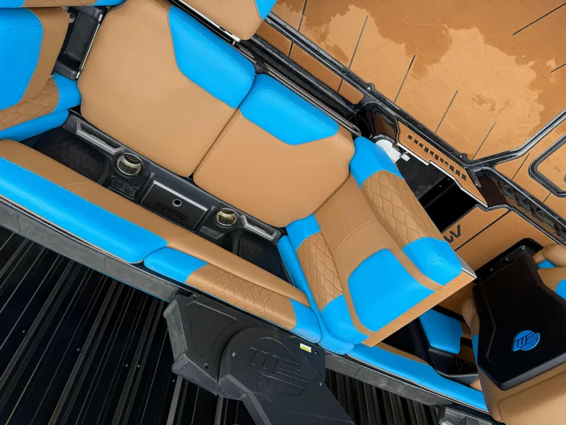 Slide: The Image of 2021 Malibu M240 boat interior with tan and blue seating, featuring cup holders and sleek design. - 9