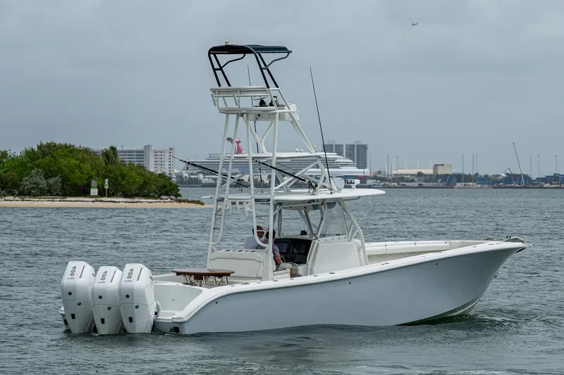 Slide: The Image of 2013 Yellowfin 39 Offshore boat with triple engines cruising near a city shoreline. - 13