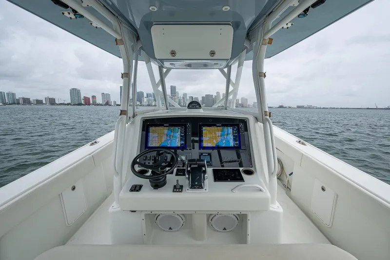 Slide: The Image of 2013 Yellowfin 39 Offshore boat dashboard with navigation screens, steering wheel, and city skyline view. - 45