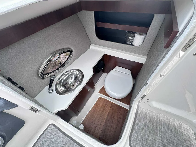Slide: The Image of 2021 Chaparral 30 Surf boat bathroom with sink, toilet, and storage shelves. - 29