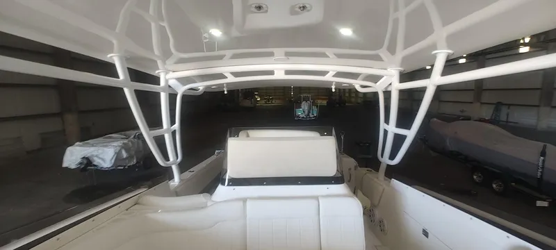 Slide: The Image of 2012 Intrepid 400 Cuddy boat interior with white seating and framework in a storage facility. - 17