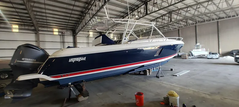 Slide: The Image of 2012 Intrepid 400 Cuddy boat in storage, blue hull, indoor warehouse setting. - 7