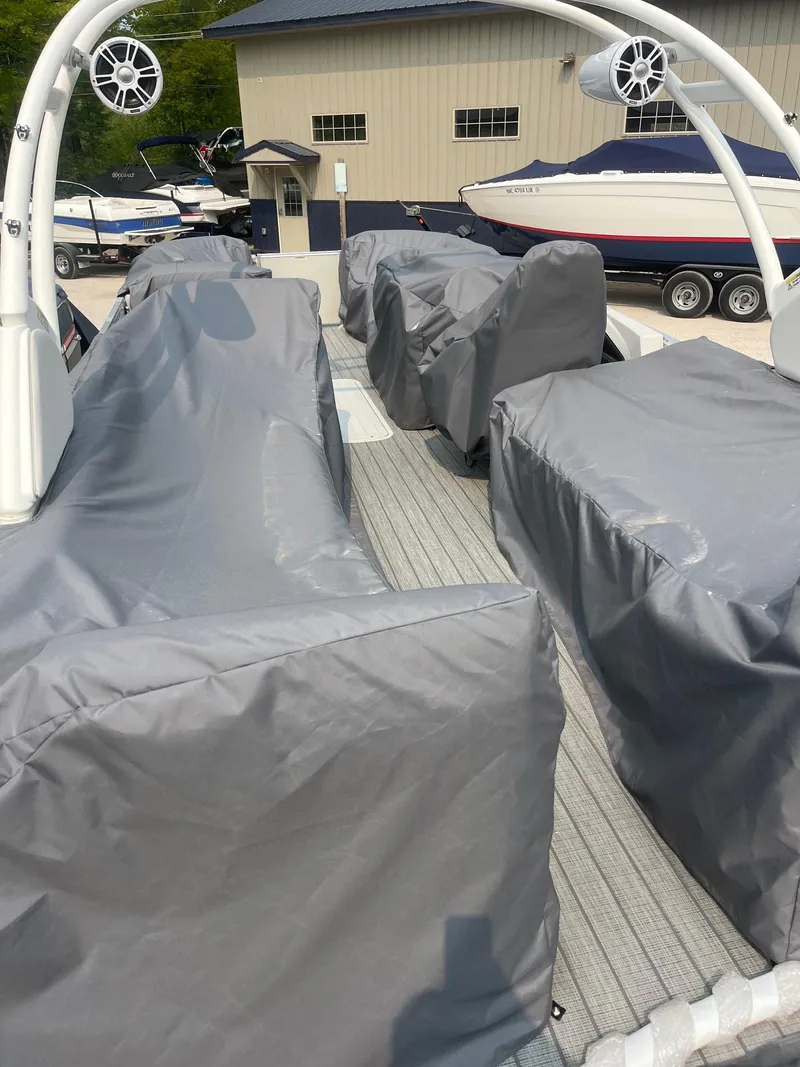 Slide: The Image of 2025 Avalon 2585 Catalina Quad Lounger Shift covered, docked near other boats. - 18