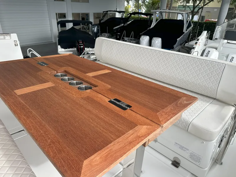 Slide: The Image of 2024 Jeanneau DB 43 boat interior with wooden table and cushioned seating. - 13