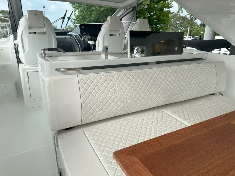 Slide: The Image of 2024 Jeanneau DB 43 interior with white quilted seating and wooden table. - 16