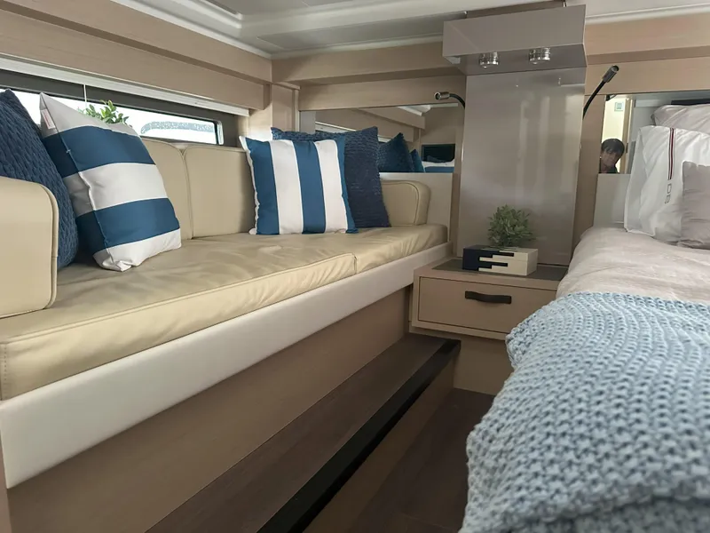 Slide: The Image of 2024 Jeanneau DB 43 interior with beige seating, striped cushions, and cozy decor. - 37