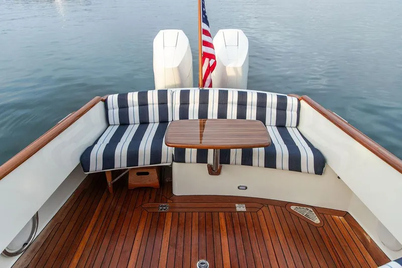 Slide: The Image of 2024 Hinckley 35 boat cruising on calm water with scenic forest backdrop. - 11