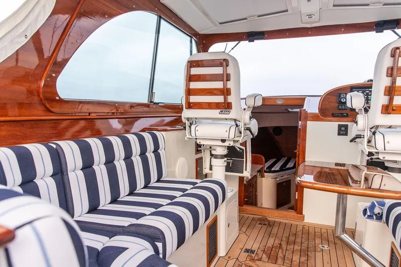 Slide: The Image of 2024 Hinckley 35 yacht with striped seating, wooden deck, and American flag on calm water. - 36