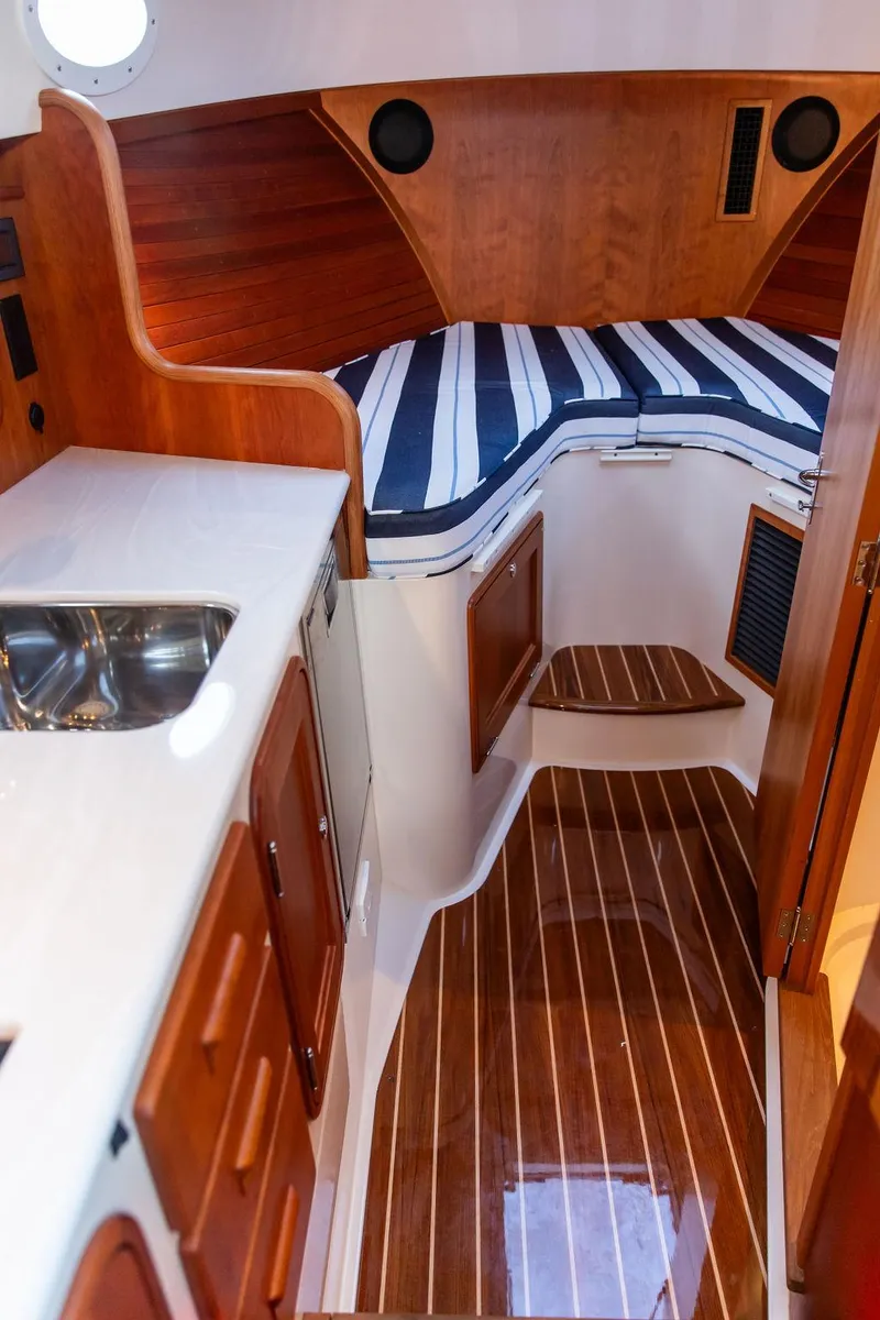 Slide: The Image of 2024 Hinckley 35 interior cabin with striped bedding and wooden paneling. - 45