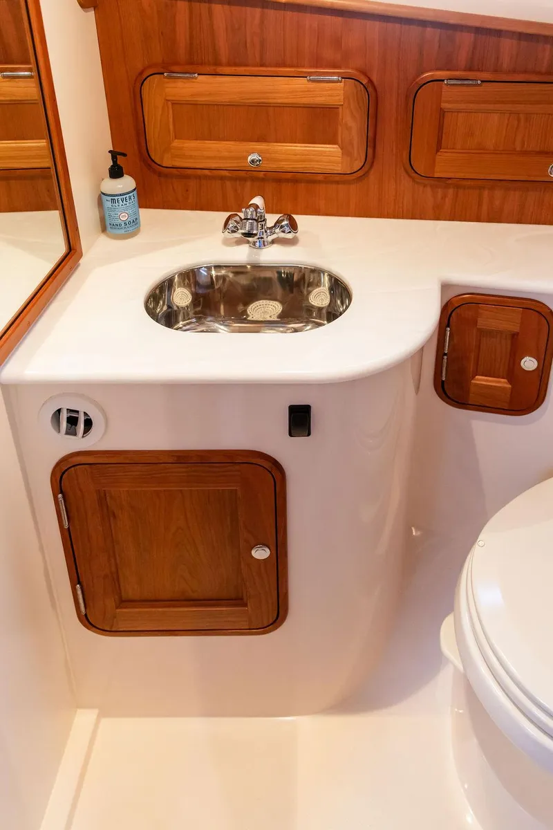 Slide: The Image of 2024 Hinckley 35 boat deck with striped seating, wooden table, and American flag. - 55