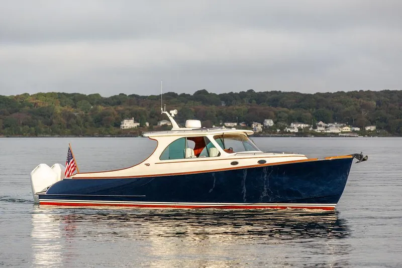 Slide: The Image of 2024 Hinckley 35 boat cruising on a calm lake with scenic shoreline background. - 6